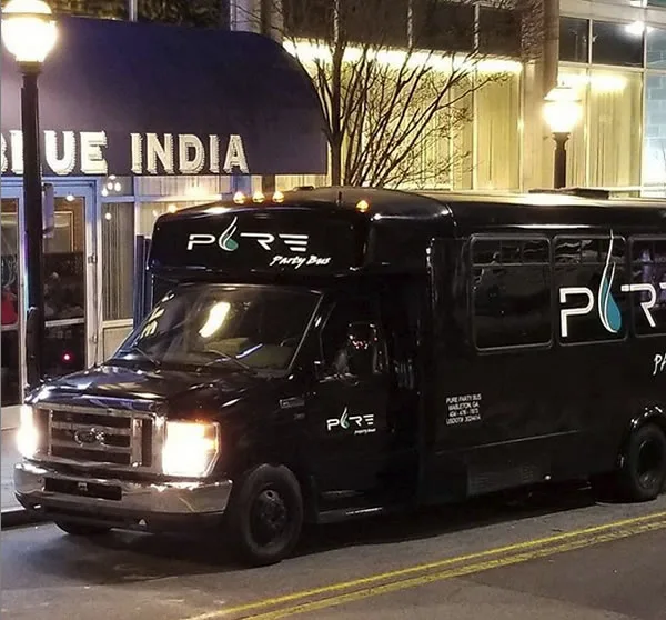 Pure Party Bus parked outside a downtown Atlanta restaurant at night