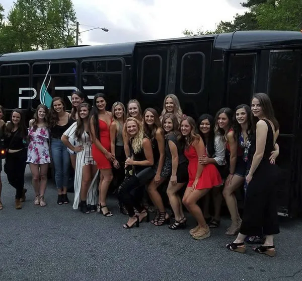 Birthday group posing in front of a black party bus