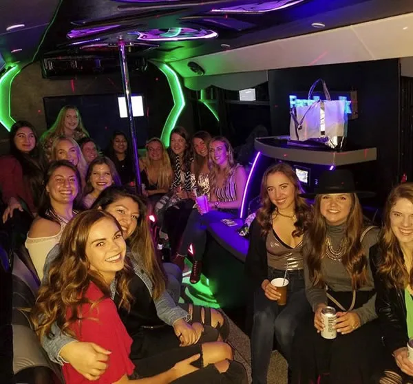 College friends celebrating inside an LED-lit party bus
