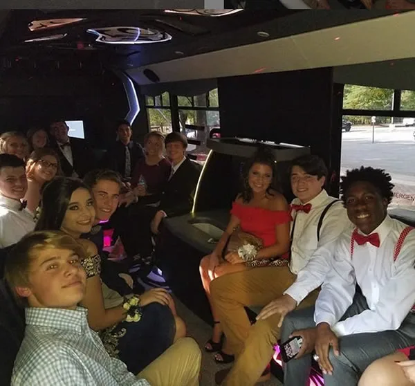 Prom group in formal wear seated inside a party bus